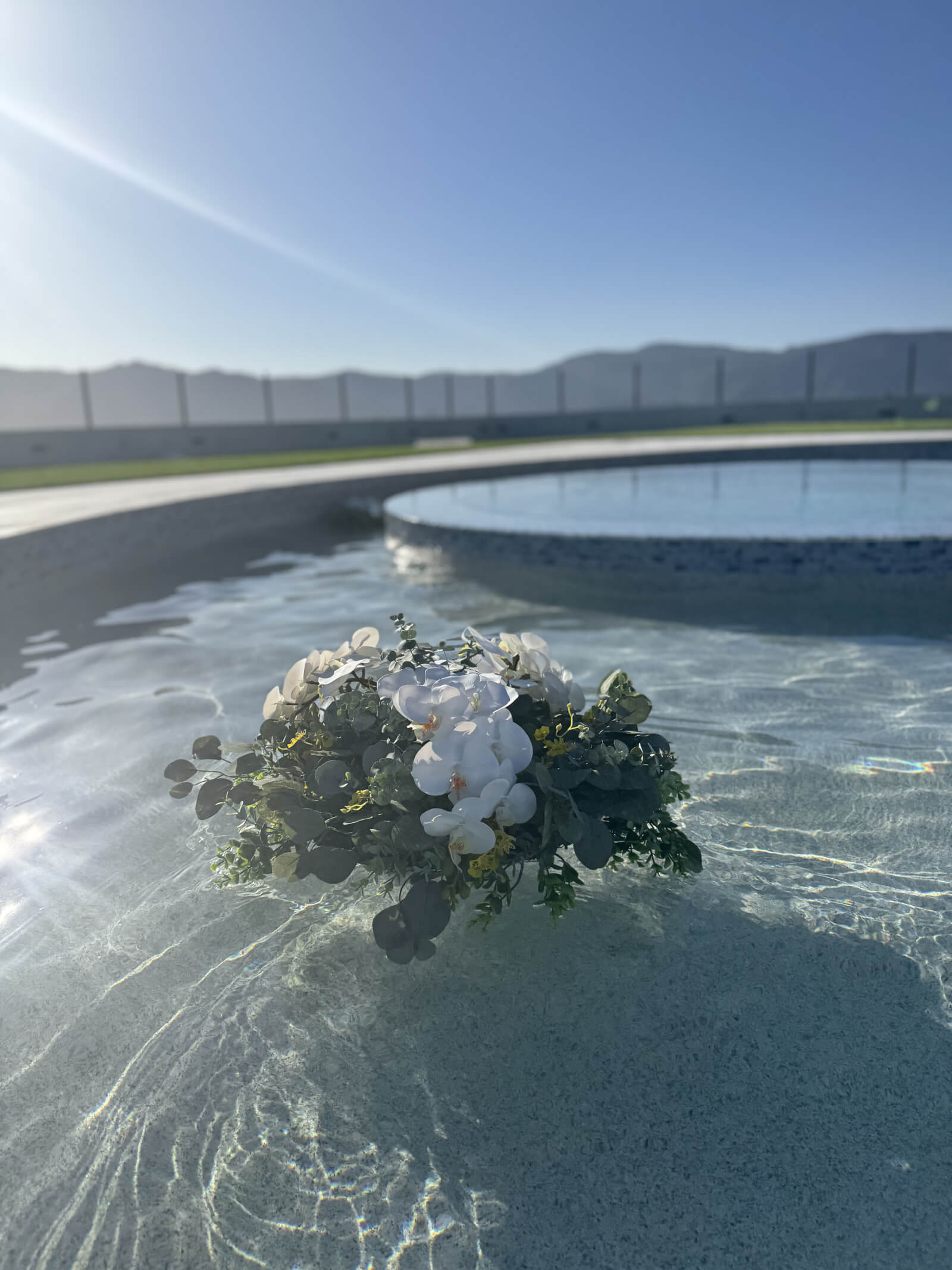 Single floating bouquet on a still pool at a wedding