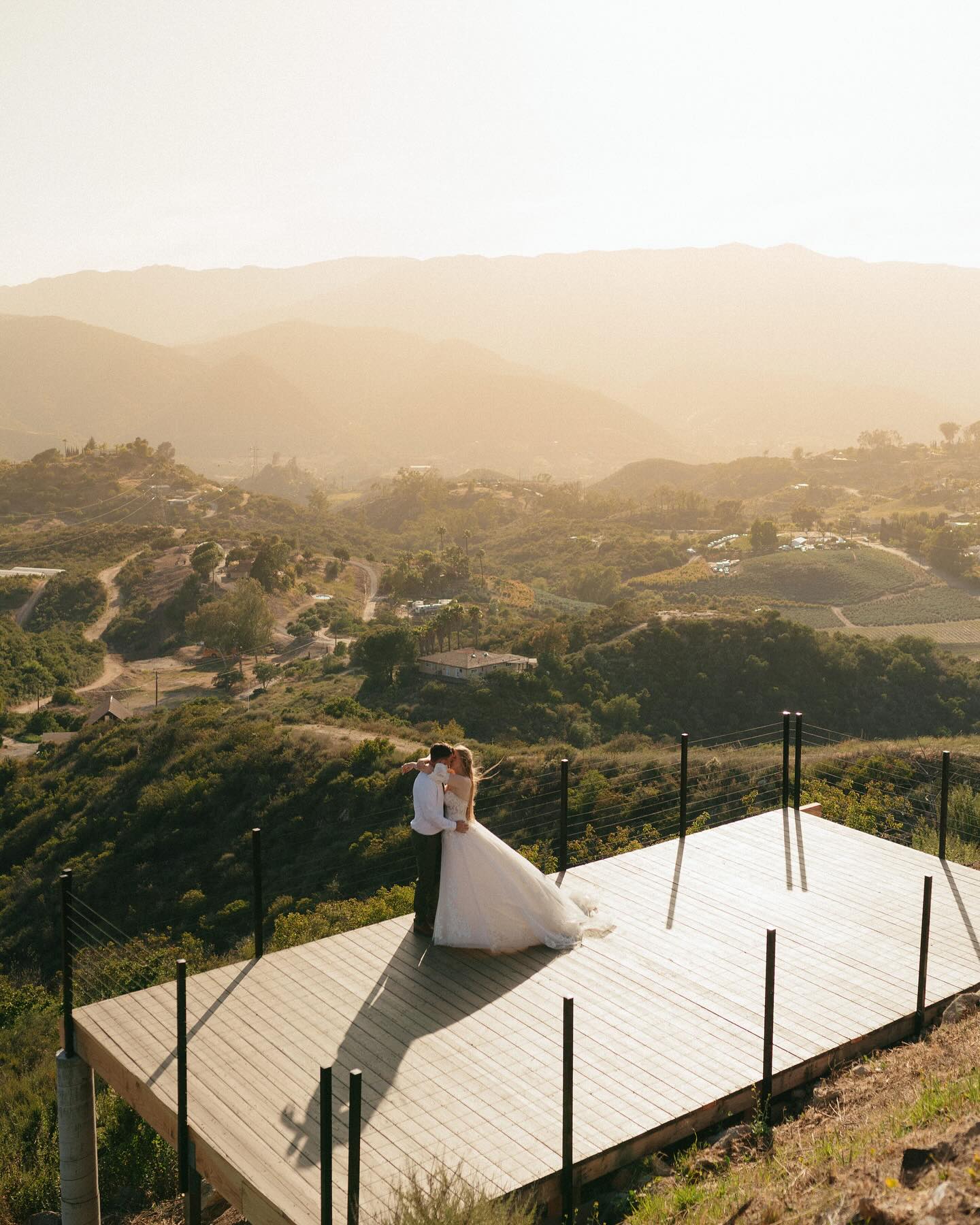Couple at a cliffside ceremony deck overlooking the San Diego mountains at golden hour